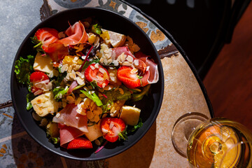 Salad with prosciutto, strawberries, mango, cheese, almond slices, arugula