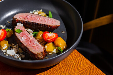 Grilled pork steak with strawberries, almond slices, mint, mango and sauce