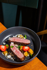 Grilled pork steak with strawberries, almond slices, mint, mango and sauce