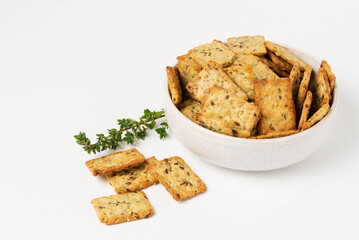 Homemade diet square cookies with spices on a white background. Herbal crunchy crackers with green thyme isolated