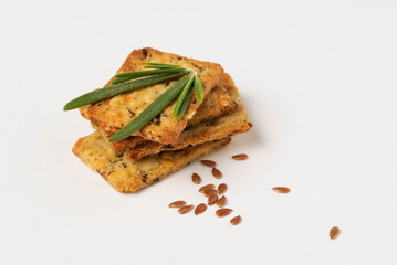 Macro photo of square cookies with spices, herbs and flaxeed white background. Herbal crunchy crackers with green rosemary  and flax seeds isolated