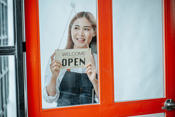Back view glass door small business owner holding a sign to open a shop