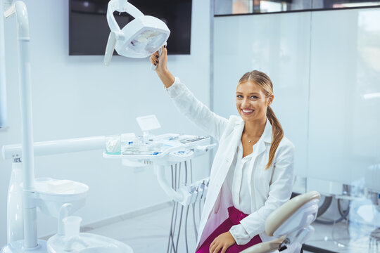People, medicine, stomatology and healthcare concept - happy young female dentist with tools over medical office background. Portrait of female dentist smiling with arms crossed in dental clinic