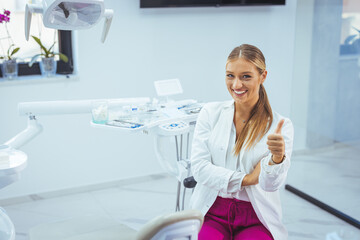 Portrait of a Caucasian woman dentist, sitting in her office next to a dentist chair, smiling. Portrait of female dentist. She standing at her office. Healthcare and medicine concept
