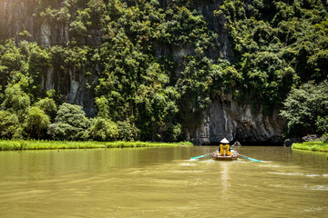 Mujer remando en rio de excursion Tam Coc, en Ninh Binh, Vietnam