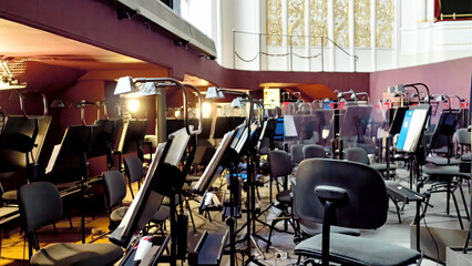 Orchestra pit of the Opera and Ballet Theatre. A break in the rehearsal of musicians in the orchestra pit. Music stands, chairs, music notes under the theater stage. Arrangement of an orchestra pit.