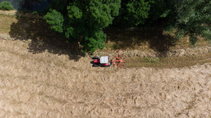 Tracteur en bordure de champ travaillant l'andainage. Agriculteur faisant les foins en début...