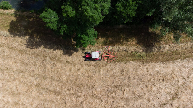 Tracteur en bordure de champ travaillant l'andainage. Agriculteur faisant les foins en d&eacute;but d'&eacute;t&eacute;.