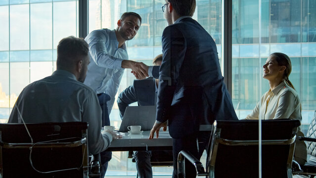 Young business negotiators shaking hands with partners after closing a deal in a modern office