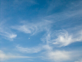 The moon began to rise in the sky, white cirrus clouds frame this still small moon, an abstract picture is created, a beautiful sky landscape