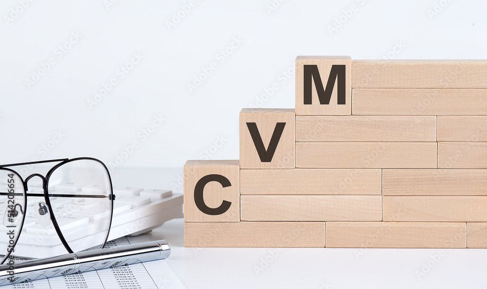 Poster wooden cubes with letters cvm on the white table with keyboard and glasses