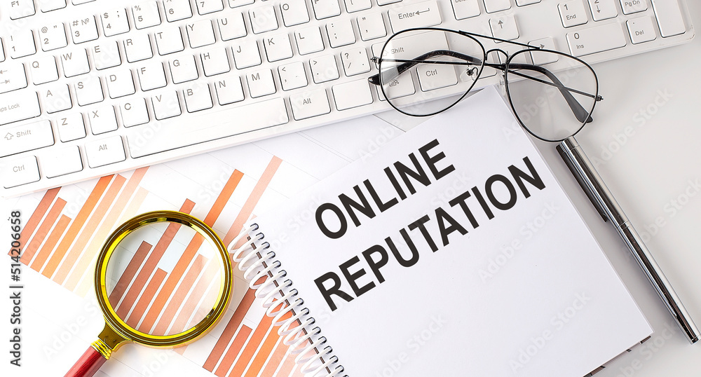 Poster online reputation text written on a notebook with keyboard, chart,and glasses