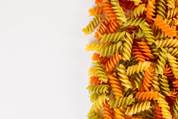 Colored fusilli or rotini variety of helical shapes pasta on a white background  with copy space
