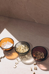 Organic bio supplements, vitamin D, calcium, in round glass bowls on a stone beige table with a shadow from the sunlight. Healthy lifestyle