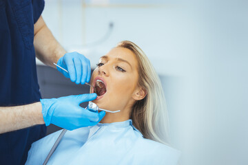 Perfect smile! Part of dentist examining his beautiful patient in dentist office. European young woman smiling while looking at mirror in dental clinic