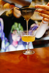 the bartender prepares an orange cocktail