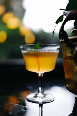 an orange cocktail is standing next to the greenery. straight view