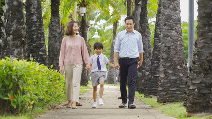 Portrait of happy smiling Asian Family walking together in public garden park in family relationship on vacation. Love of father, mother, and son. People lifestyle.