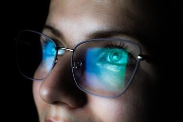 Girl works on internet. Reflection at the glasses from laptop..Close up of woman's eyes with black...