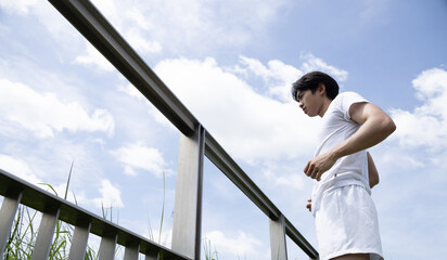 Young asian man in white shirt stretch body in park. Concept for health lifestyle in park.
