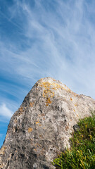 Rocas graniticas con manchas de liquen amarillo en el litoral bajo cielo azul