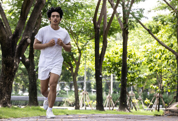 Asian handsome man in white shirt running in park. Concept for health lifestyle in park.