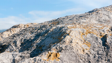 Rocas graniticas con manchas de liquen amarillo en el litoral bajo cielo azul