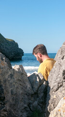 Hombre leyendo un libro en playa rocosa junto a horizonte marino