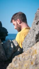 Hombre leyendo un libro en playa rocosa junto a horizonte marino