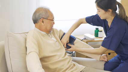 Obraz premium Happy woman nurse, daughter check up body of sick old senior elderly patient lying on bed in bedroom in home or house in medical and healthcare treatment. Asian Thai people lifestyle. Family