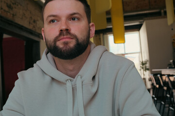 tired millennial man in casual clothes deep in thoughts at the cafe at lunchtime