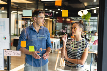 Creative caucasian businessman and biracial businesswoman planning business strategy in office