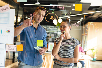 Caucasian businessman discussing business strategy with biracial businesswoman in office