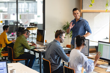 Smiling caucasian manager motivating customer service representatives in office