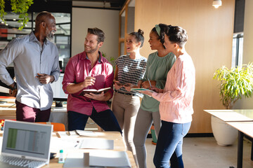 Happy multiracial male and female colleagues discussing in meeting at office