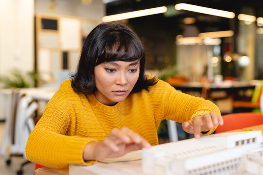 Biracial yfemale architect examining architectural model in creative office