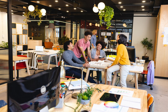 Multiracial male and female architects with architectural model in office