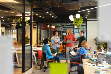 Multiracial businessmen and businesswomen discussing during meeting in creative office