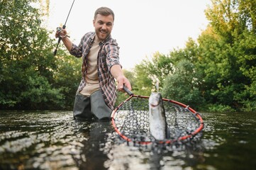 Fly-fisherman holding trout out of the water