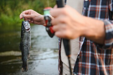 Fly-fisherman holding trout out of the water
