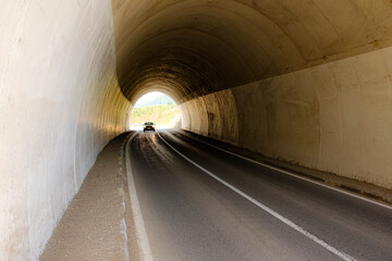 car passes through a local tunnel in the mountains, day