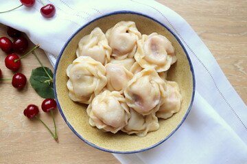 delicious sweet dumplings with cherries in a clay plate close-up on the table selective focus