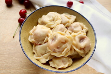 delicious sweet dumplings with cherries in a clay plate close-up on the table selective focus