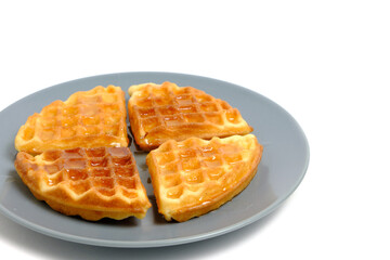 Soft muffin waffles, poured with fresh honey in plate on white background.