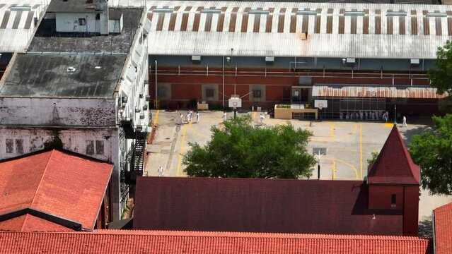 Prison inmates in jumpsuit uniforms at jail. Jailhouse yard in America. Texas prison system in Huntsville Texas. Aerial truck shot.