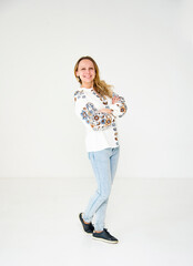 portrait of beautiful smiling young woman in ukrainian  white embroidery posing in white studio