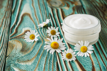 Chamomile cream in glass jar on the wooden background