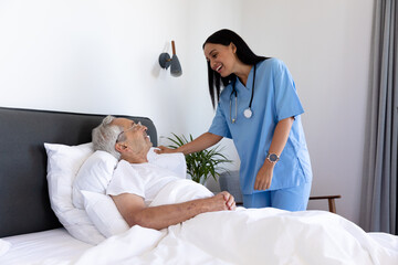Biracial female health worker talking to caucasian senior man lying on the bed - Powered by Adobe