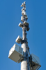 Fototapeta na wymiar Telecommunication cell tower antenna against blue sky. Wireless communication and modern mobile internet. Bottom view.