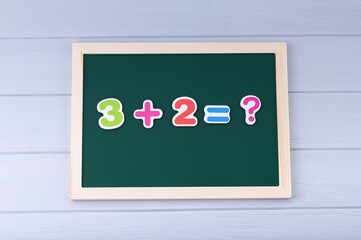 School board with magnetic numbers. Solving examples. Math for kids